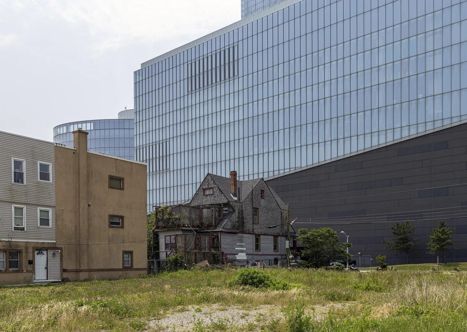 Older houses beside an open lot in Atlantic City, with a casino tower behind them