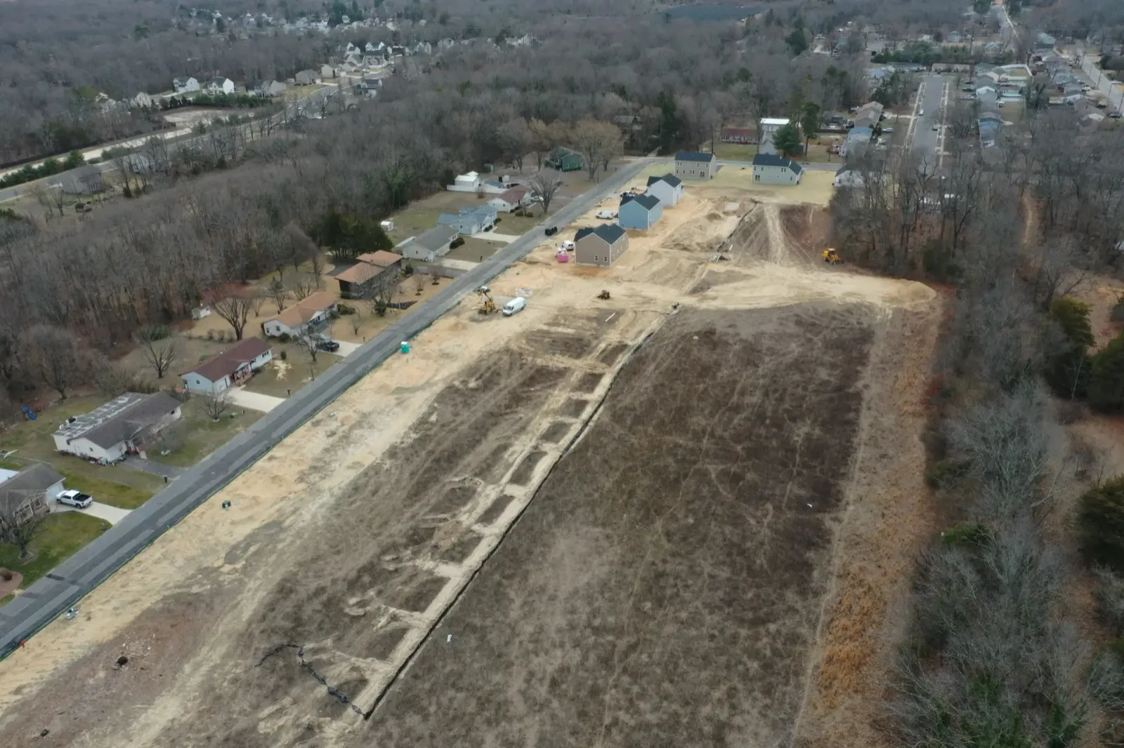 Aerial view of cleared ground beside a road, with new homes going up along its edge
