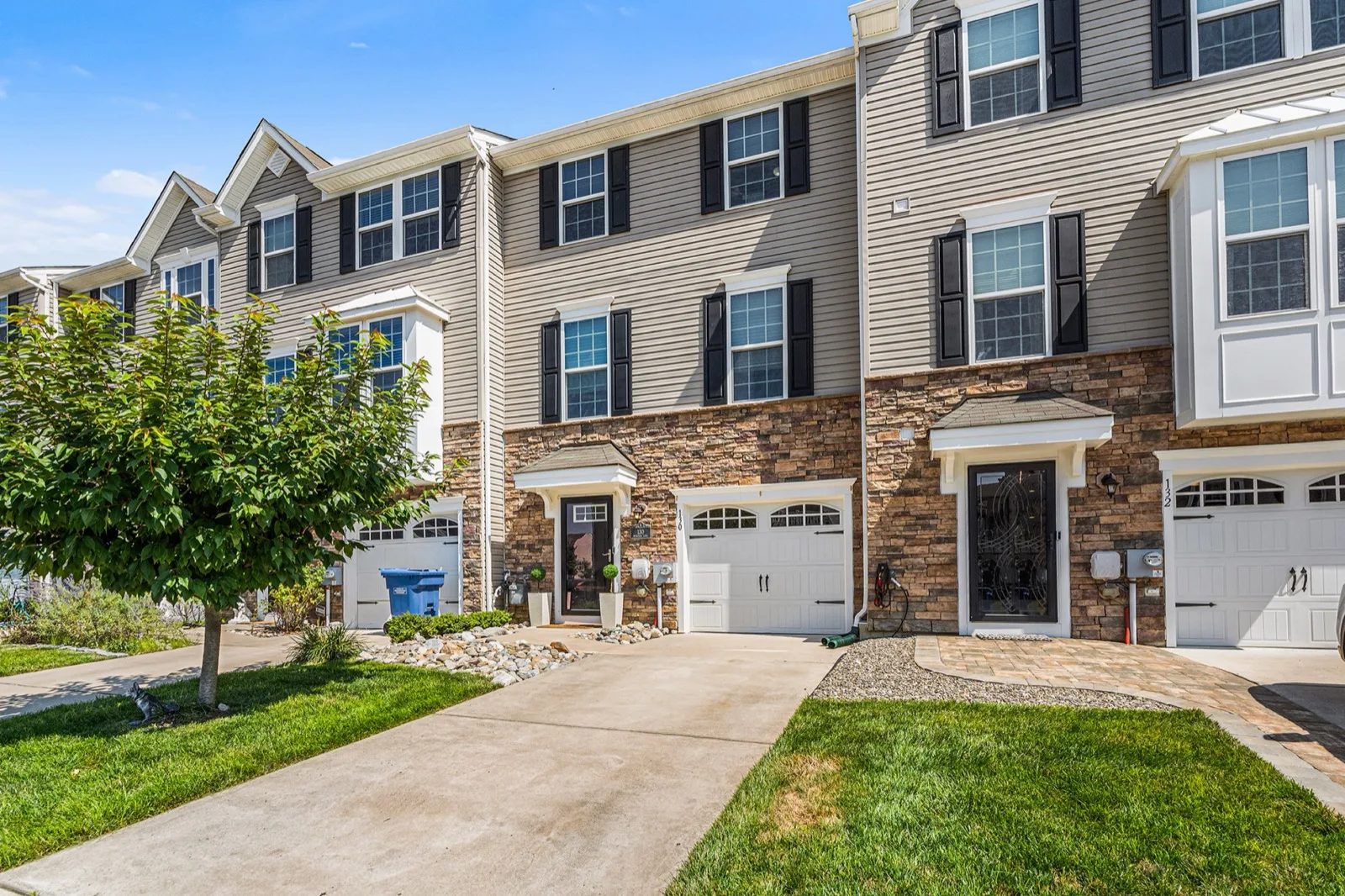 A row of three story townhomes with garages and stone fronts in Sewell, Washington Township, New Jersey