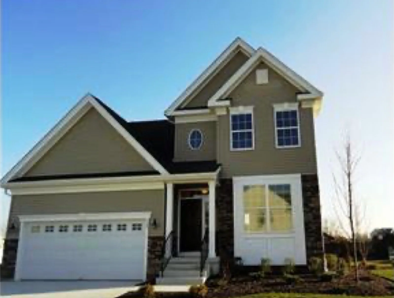 A finished new construction home with a two car garage on a lot that has not grown in yet
