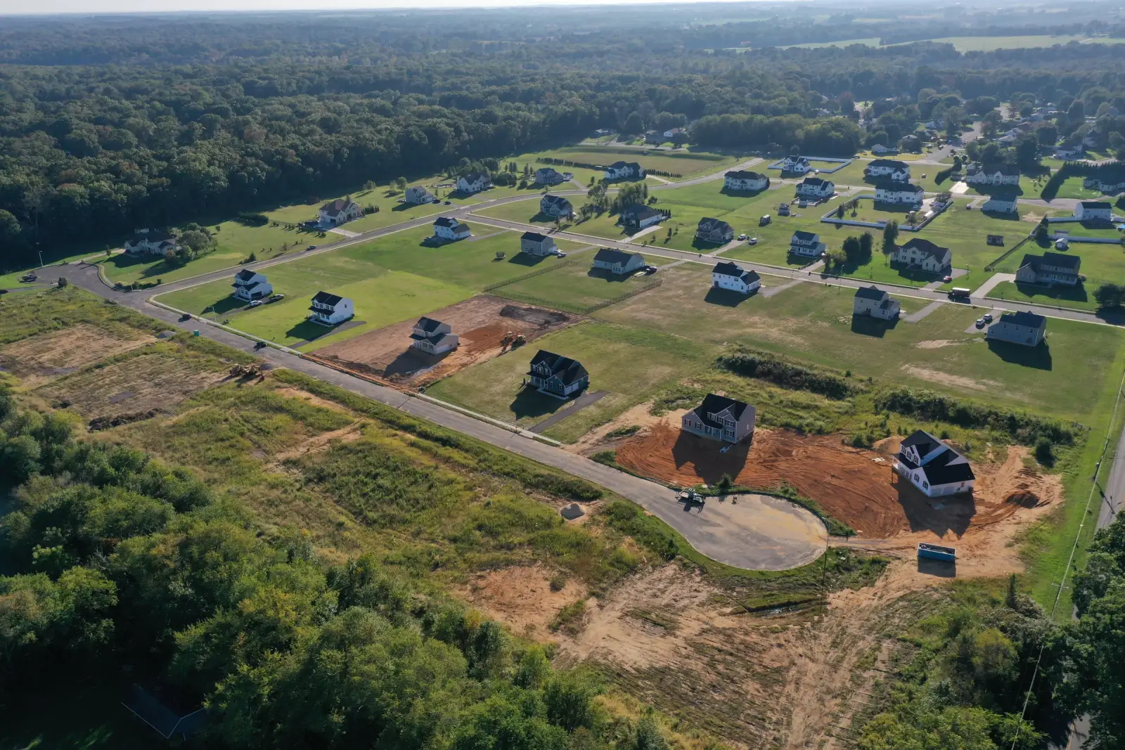 An aerial of a new-home neighborhood with houses under construction on cleared pads